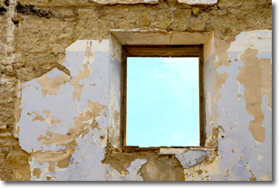 Window in cracked wall showing beautiful blue sky